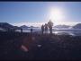 Des randonneurs contemplent une chaine chargée de glaciers et éclairée par le soleil de minuit.